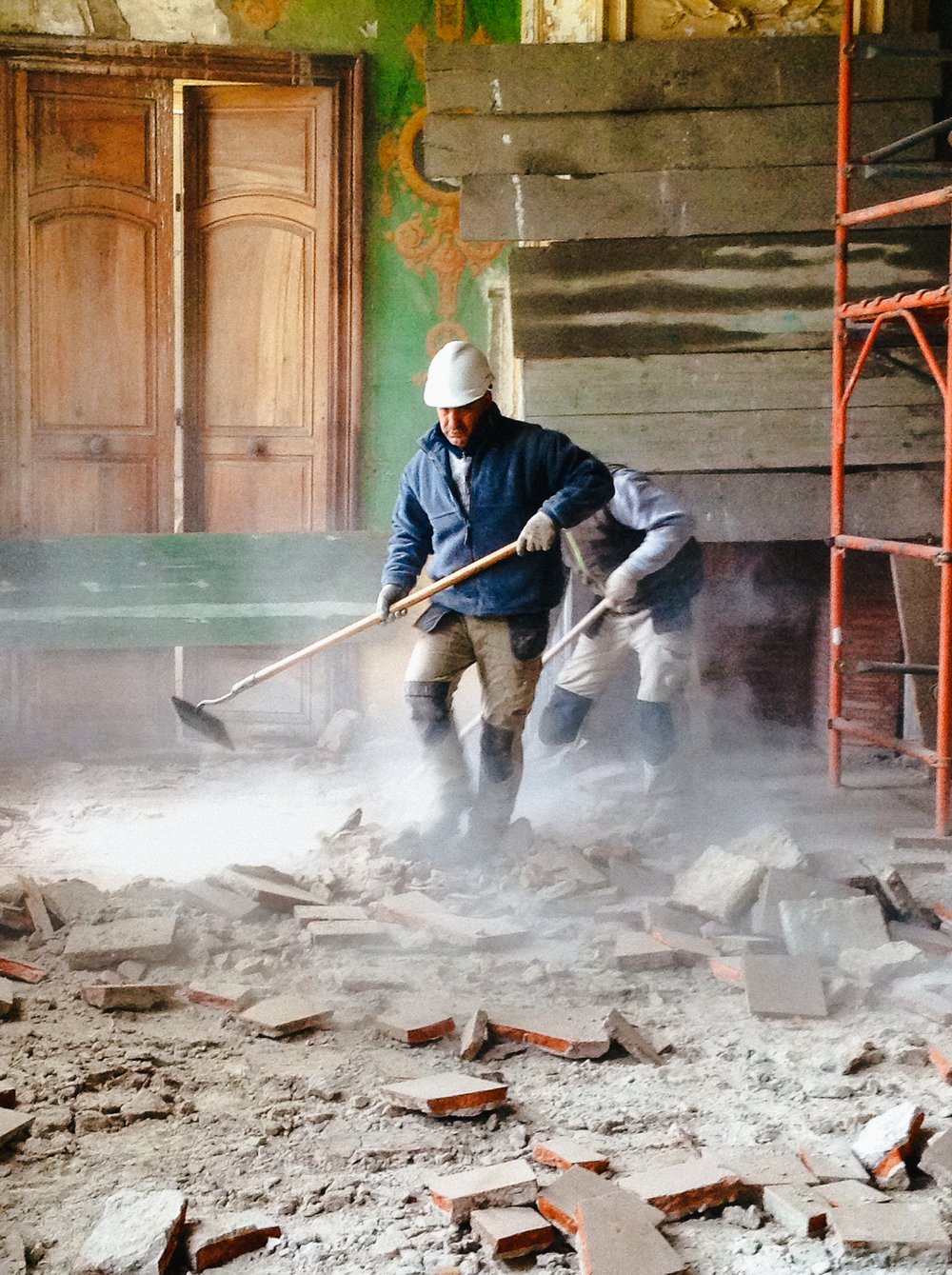A worker clearing rubble from a floor