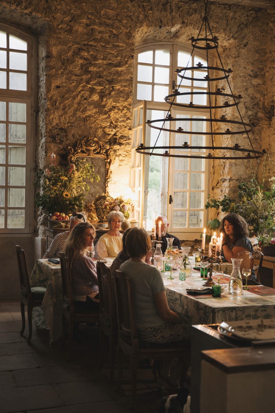 A workshop group at the long table by candlelight, beneath an iron chandelier