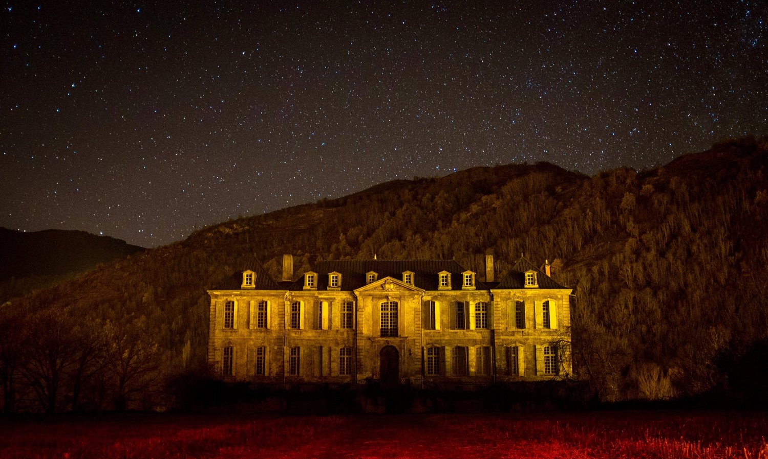 The château lit at night, under the stars